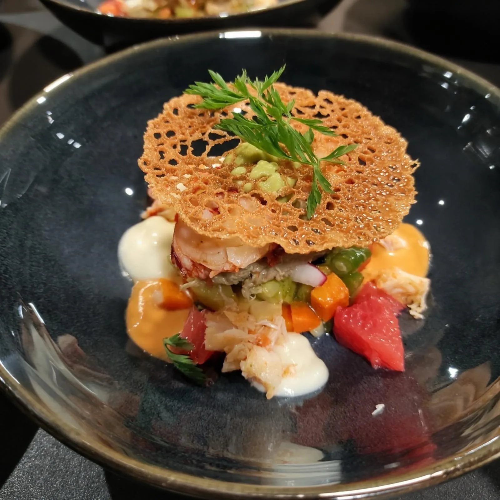 Crevettes et crabe sous une tuile dentelle, bisque et pamplemousse
